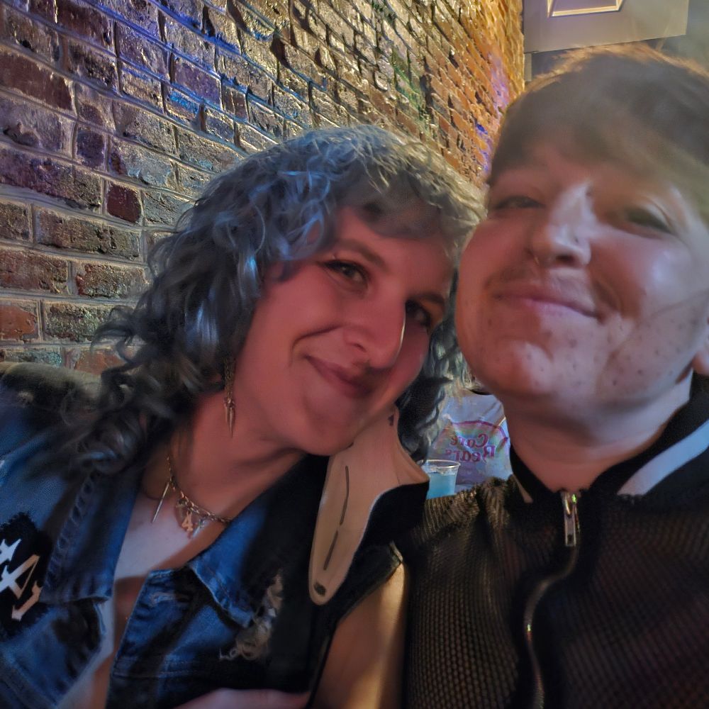 lyra and hairy poodini in front of a brick wall indoors