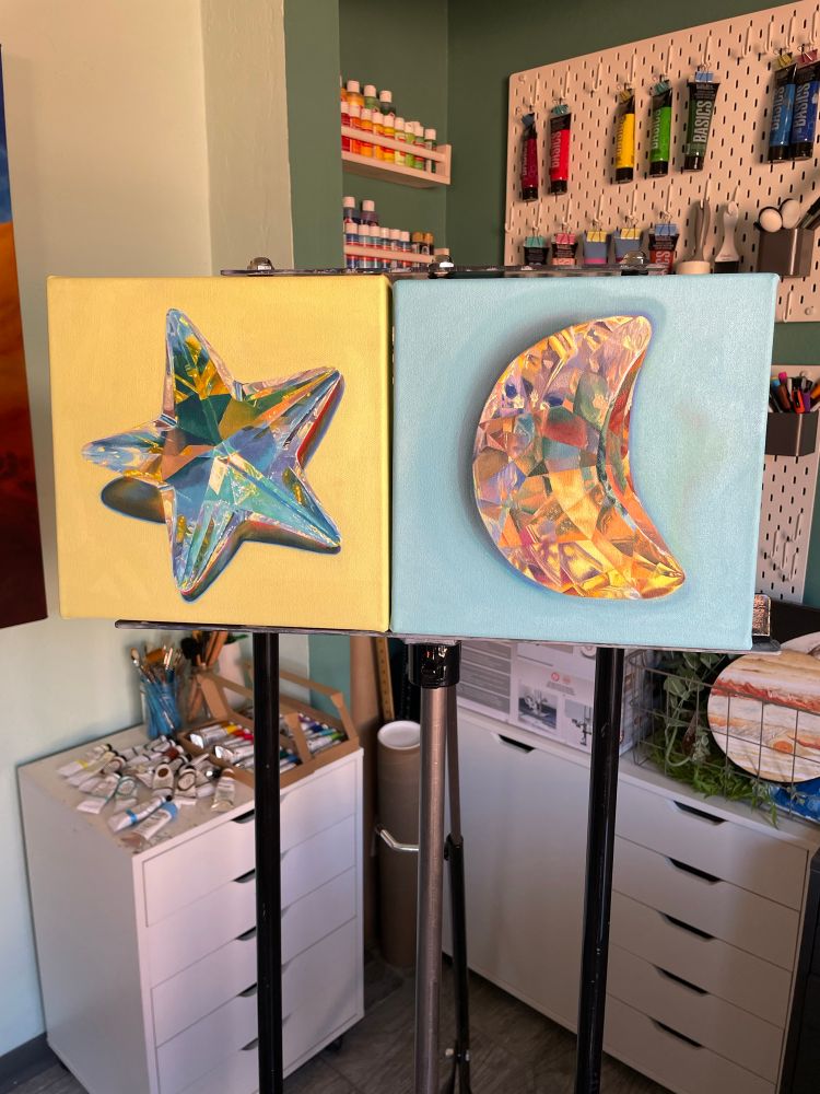 Two 10x10” canvases on an easel. Left is a crystal star with pastel yellow background. Right is a crystal half moon with pastel blue background. 