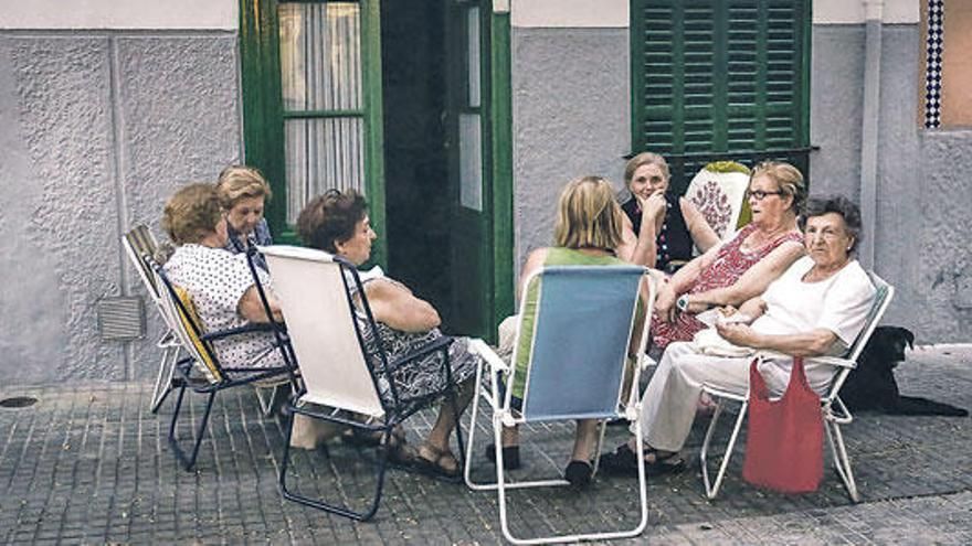 Foto de un corrillo de señoras sentadas en sillas plegables en la calle