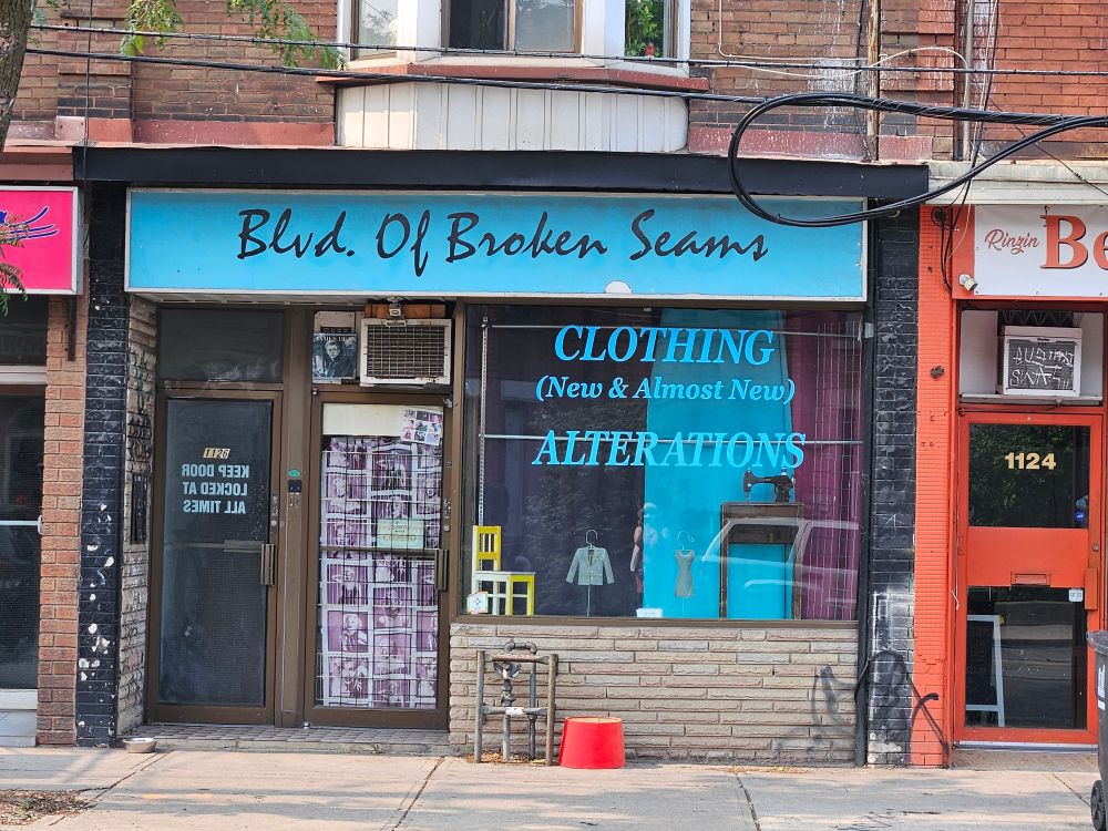 Storefront proclaiming Blvd. Of Broken Seams, with windows sign Clothing (Ew & Almost New) Alterations 