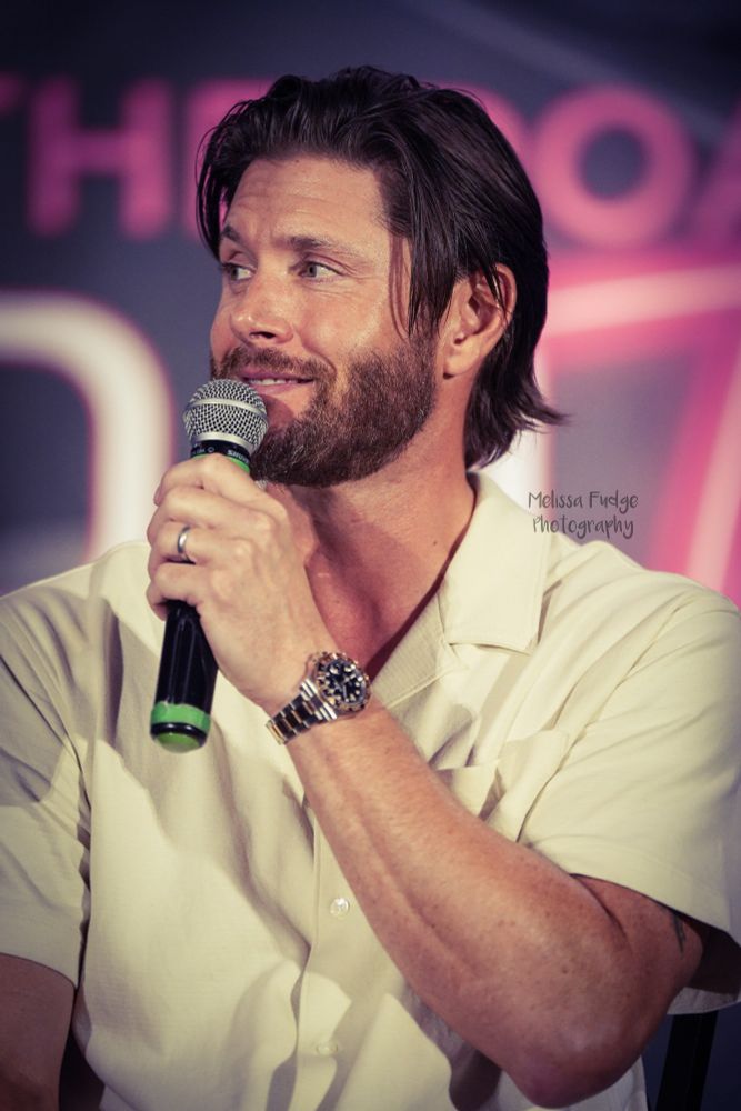 Jensen Ackles holding a microphone on stage at Creation Austin 