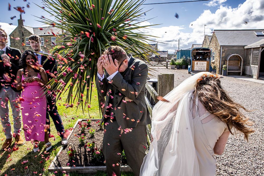 Bride and groom ducking some over-enthusiastically thrown confetti