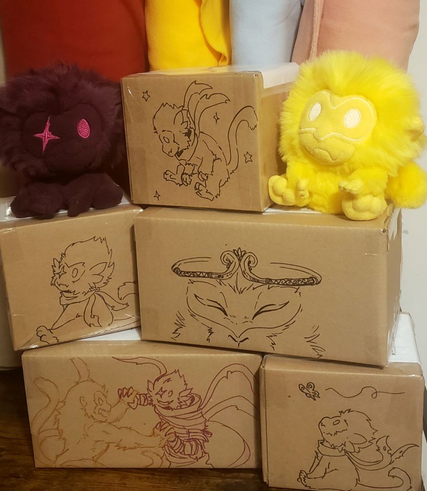 Limited edition Smokey and Harbinger plushies sit upon a stack of boxes awaiting shipment. Each box is decorated with its own unique doodle. Just a quick bit of fun. 