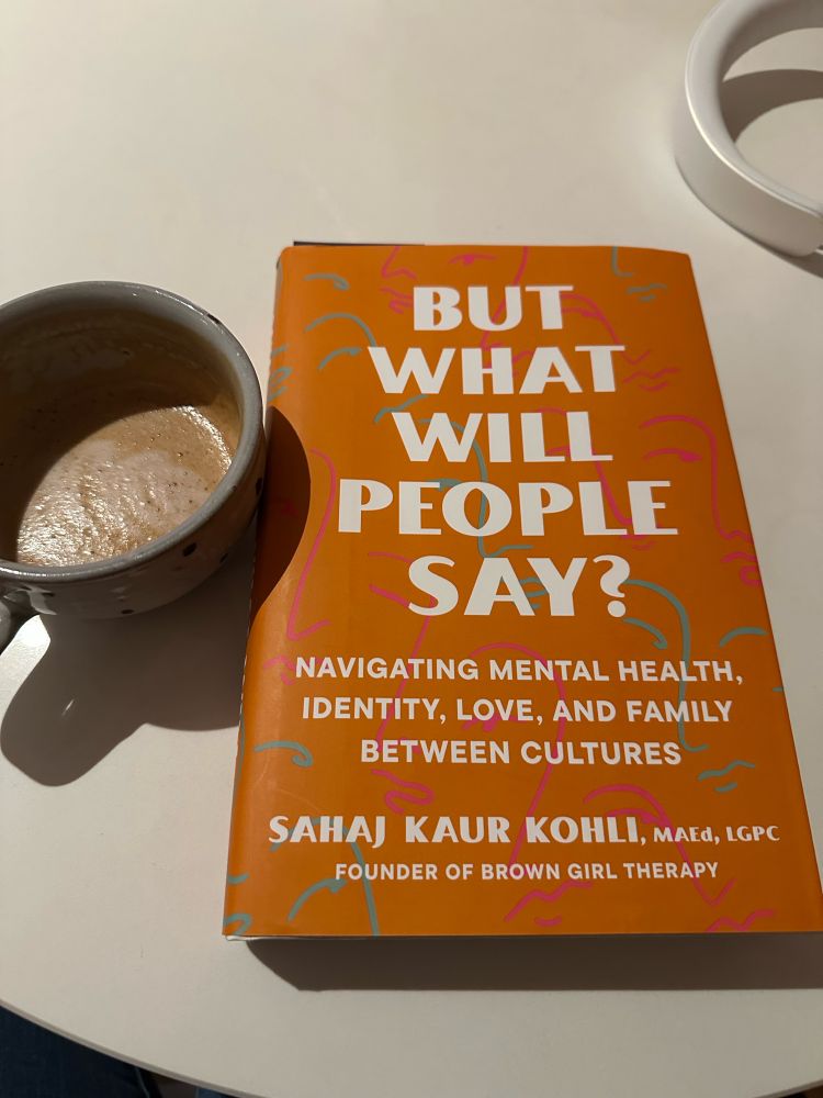 Cup of coffee next to a copy of “But what will people say?”