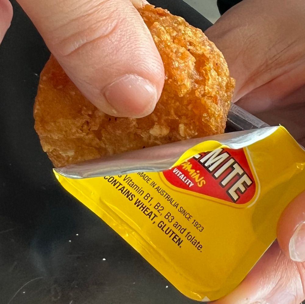 Hash brown dipped in a pack of Vegemite 