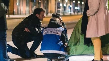 Macron accroupi s'adressant à un SDF dans sa tente.