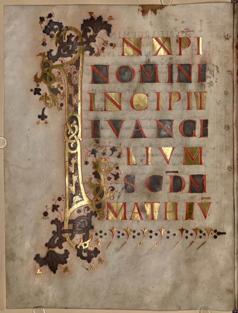 A richly decorated manuscript page with many applications in gold that are well visible because of the uneven surface of the parchment. Light reflects from these letter.