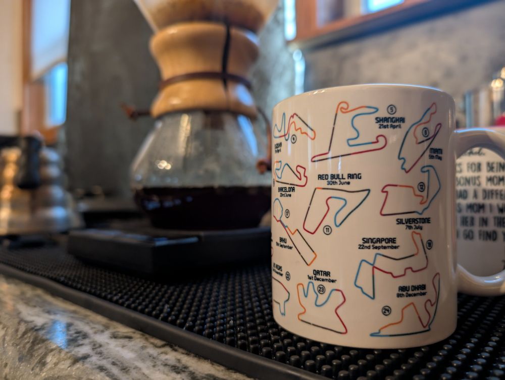 Mug with the 2024 F1 season track maps and coffee brewing in the background