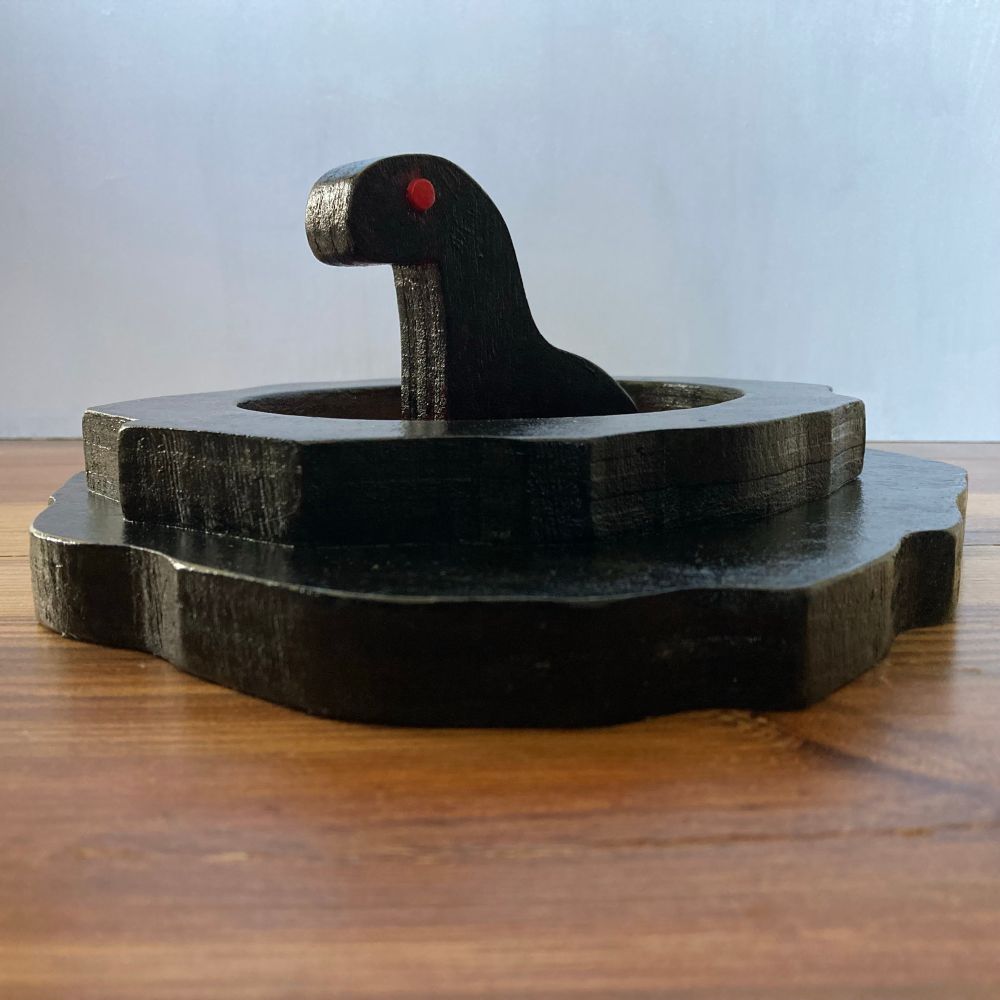 a painted wooden sculpture of a creature sitting in a pool