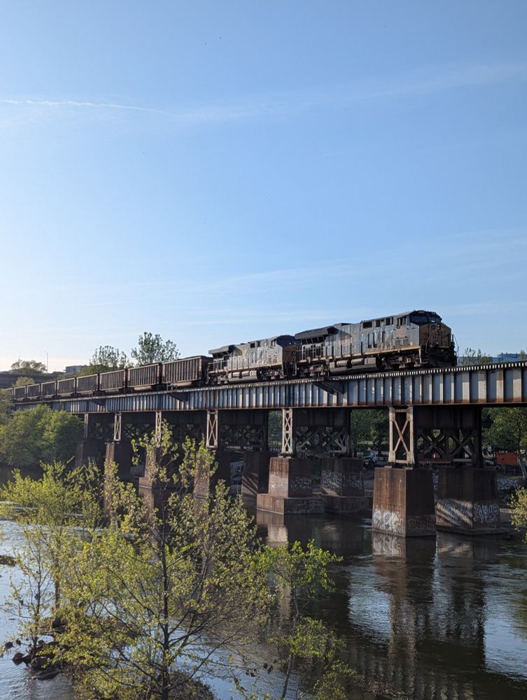 A train on a raised track running along the riverbank