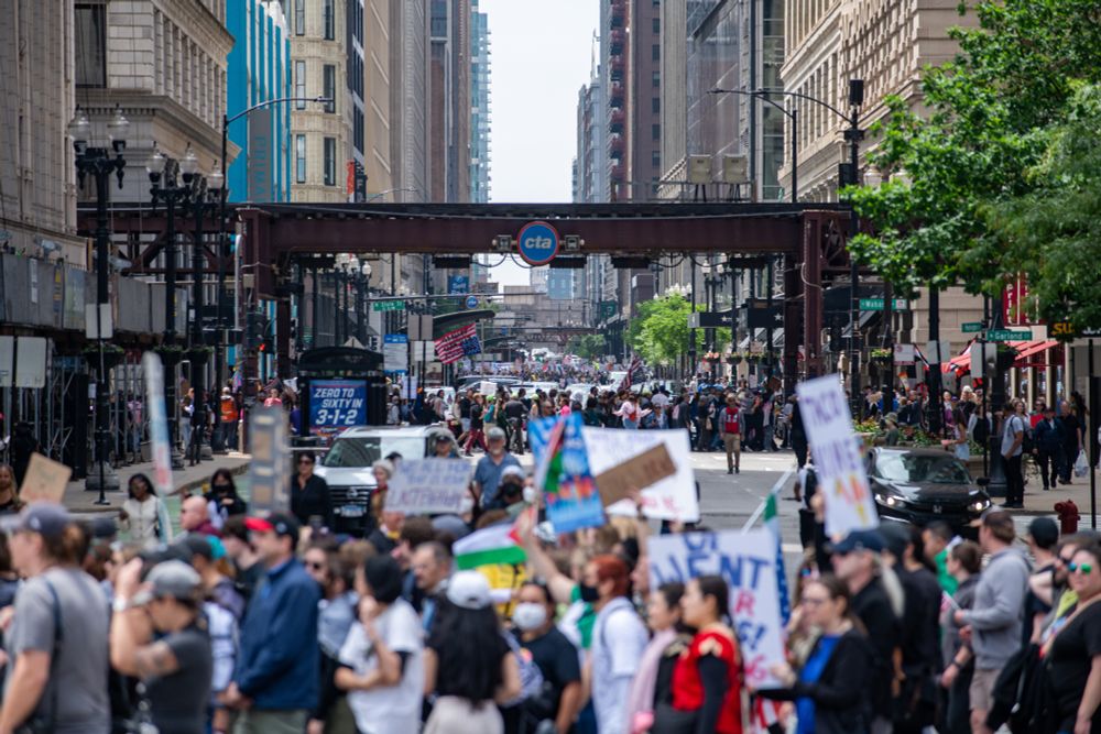 A photo of a large street demonstration in Chicago. In the center of the frame are the CTA L tracks. Below them in the front of the frame is a large group of people marching out of focus. Under the tracks in the center of the frame you can see more people streaming down the street. Further back in the far distance there are people marching down other streets. An upside down American flag is being hoisted into the air far back in the frame. 

This photo covers the distance between Michigan Ave (closest to the bottom of the frame) to at least Dearborn Aveneue down Randolph. Every block heading north and south had people marching on it. 