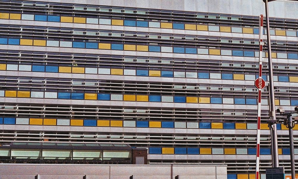 Multi story car park. Each level is faced with blue, yellow and white panels in a random order 