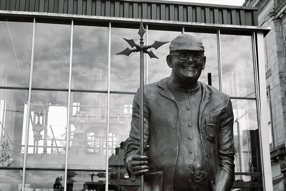 Statue of Fred Dibnah holding a lightning rod in front a replica steam engine 