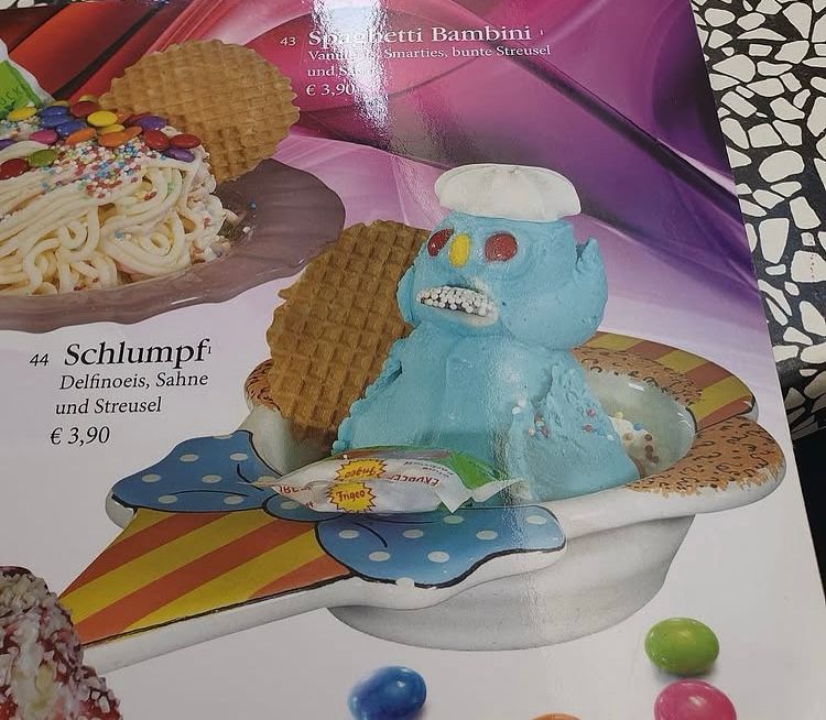 Ein Schlumpfeisbecher mit blauen Eiskugeln die zu einem recht verunglückten Männchen aufgetürmt wurden.