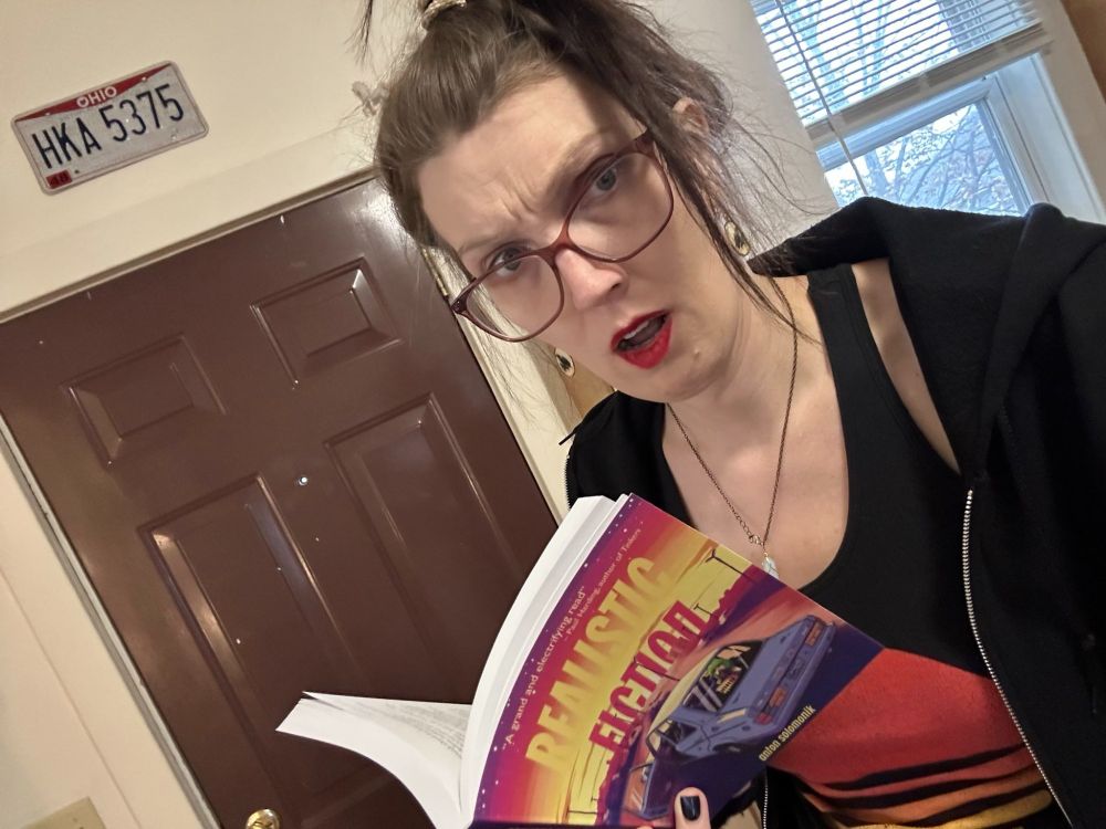 A photo of me looking up from my copy of Realistic Fiction