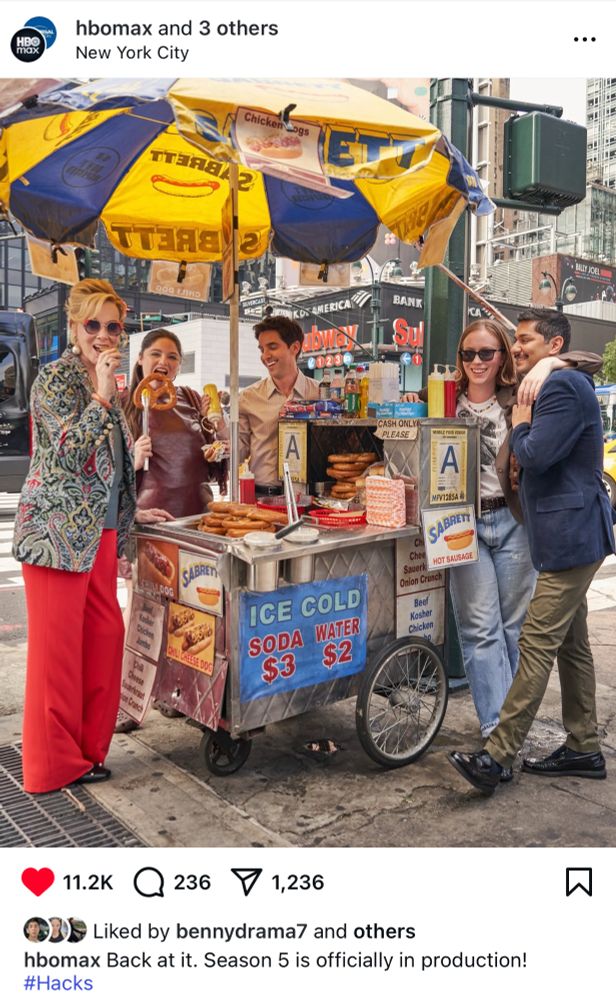 Jean Smart, Meg Stalter, Paul W. Downs, Hannah Einbinder, and Mark Indelicato standing around a pretzel cart filming Season 5 of Hacks in NYC.