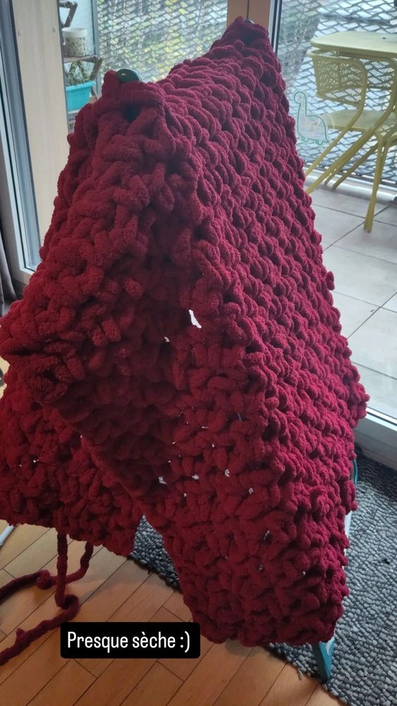 Plaid en fil doudou rouge Séchant sur un étendoir 