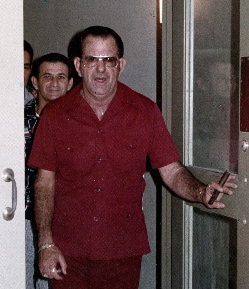 Bum Farto, a greasy looking hairy man with a cigar and gross sunglasses on. His mouth is open, and he looks like Bum Farto