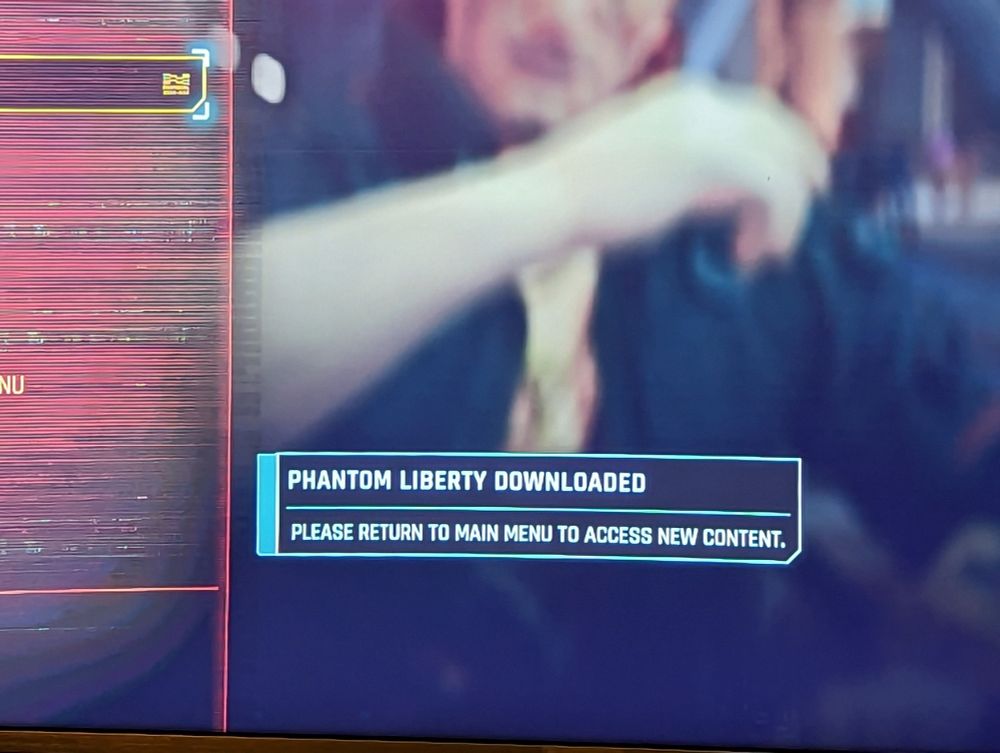 A screenshot from Cyberpunk 2077's pause screen with the message: Phantom Liberty downloaded. Please return to main menu to access new content