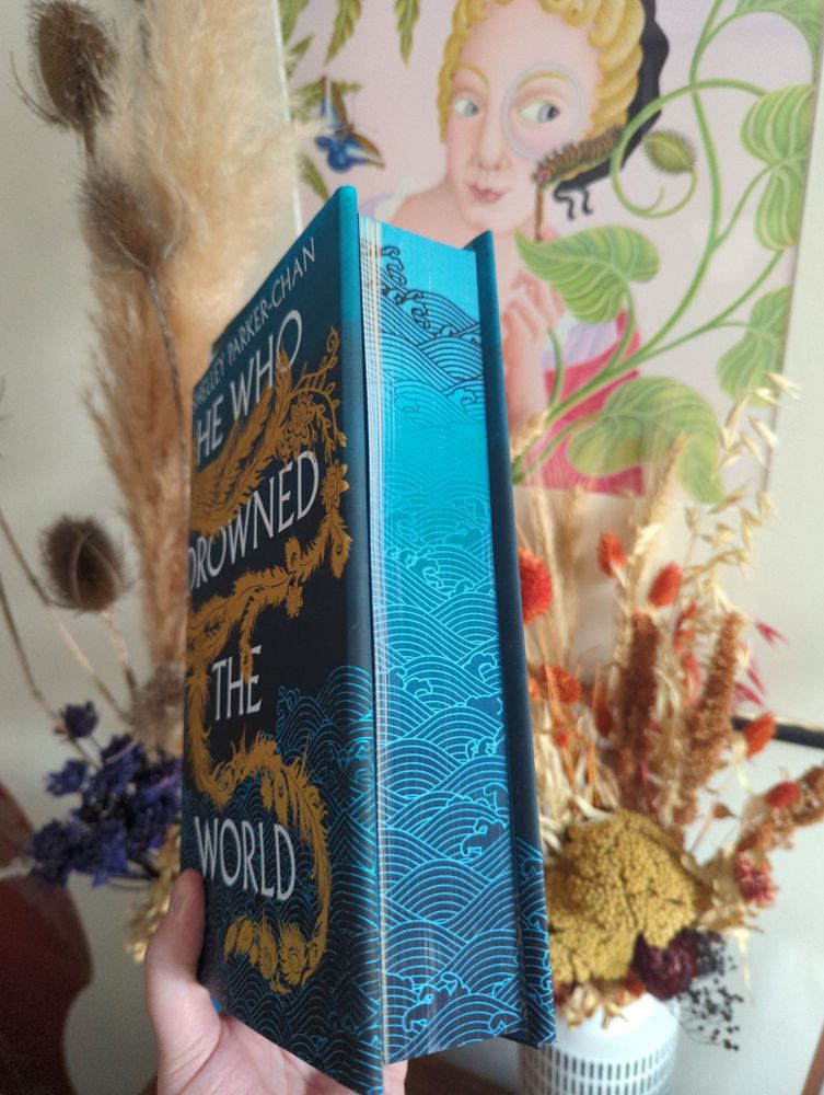 The stencilled edges of the Illumicrate edition of He Who Drowned the World by Shelley Parker-Chan - dark and light blue wave pattern