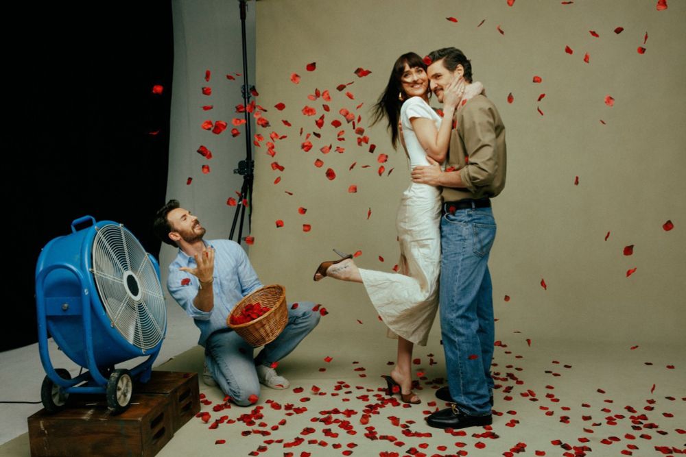 Chris Evans, Dakota Johnson, and Pedro Pascal in promotion photos for the upcoming movie The Materialists. Chris is throwing arose petals in front of a fan as Dakota embraces Pedro. 