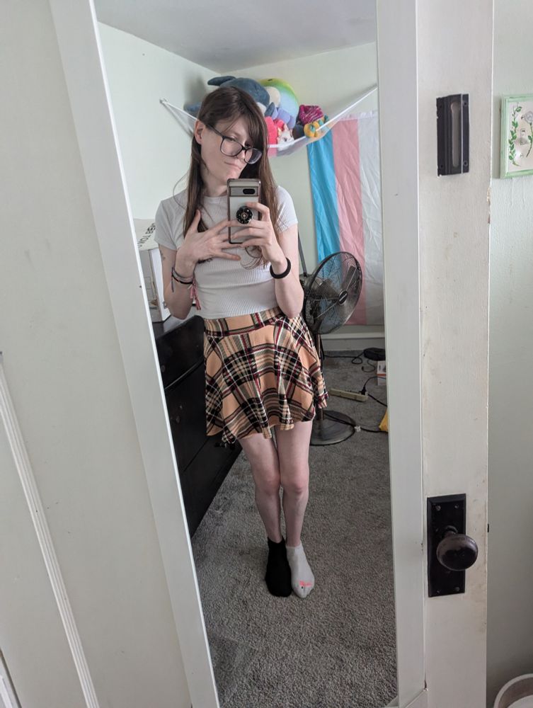 Girl with long brown hair, a pink plaid skirt and white top