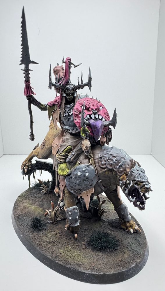 Photograph of an orruk with a pink shield riding a great gnashtoof in a white box 