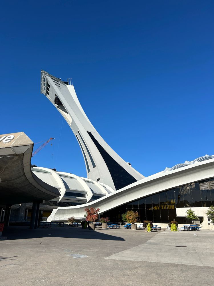 The Olympic stadium’s tower in Montréal photographed with a lot of swoopy rooflines in the foreground & an extremely clear blue sky