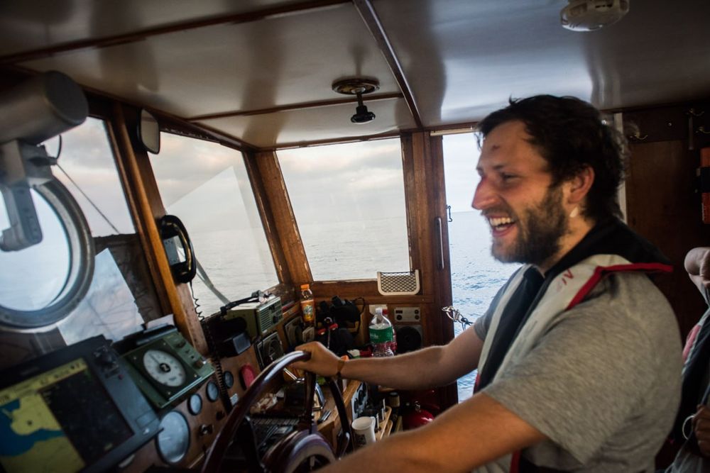 Man sieht ein Crewmitglied auf der Brücke der Sea-Watch am Steuer 