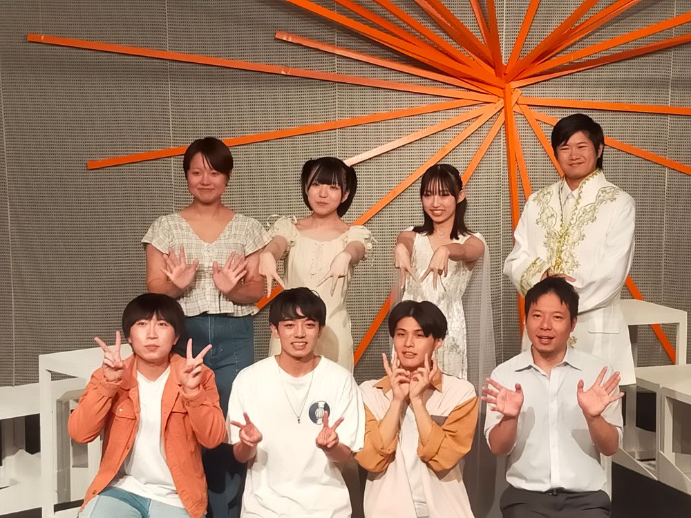 終演後のキャスト集合写真。
舞台上に8人が並び、ピースサインなどポーズを取っています。