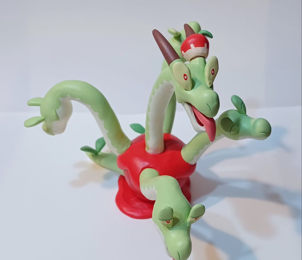 Sculpture of Hydrapple from Pokemon, each face is making a different expression. The main face looks surpised and has it's tongue stuck out.