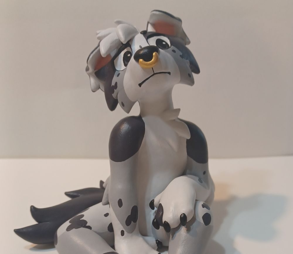 Anthro dog sculpture sitting down in a cool pose with one arm resting on a propped up leg. They are looking down and off to the side with a cool expression.