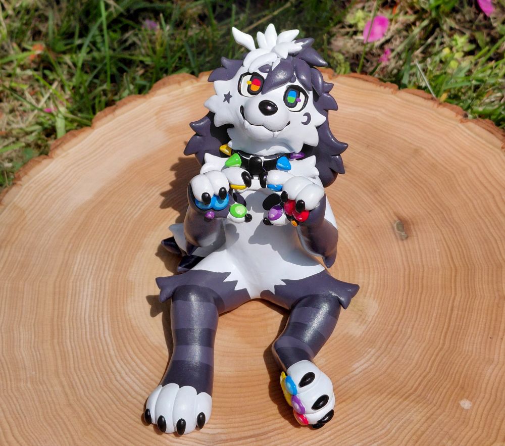 Anthro puppy sculpture sitting on a real large cut of wood that looks like a tree stump, they are doing a heart hands pose and smiling.