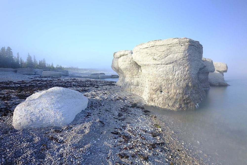 Mid-afternoon sun starts to break through the fog and cast direct light on the white monoliths on one of the many islands of the Mingan archipelago in northeast Quebec Canada. 