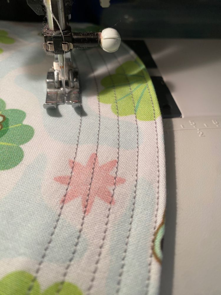 The brim of a hat under the sewing machine needle, sewing lots of lines.