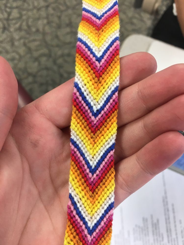 A large chevron friendship bracelet. The colors include white, many shades of yellow, orange, light brown, red, pinks, and dark blue