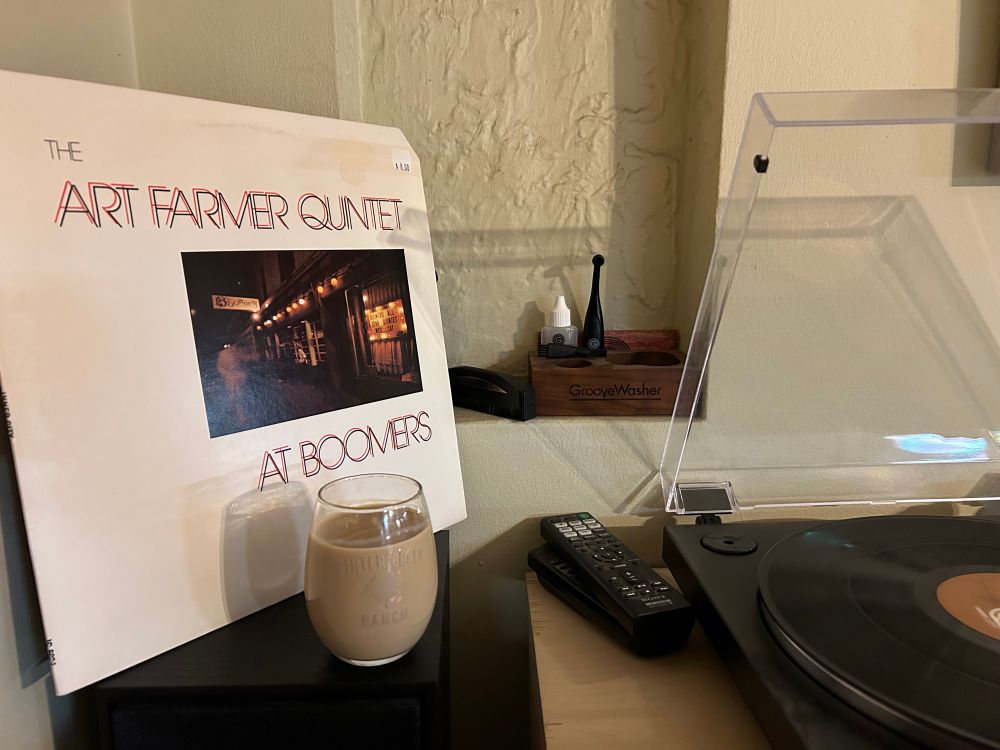 A photo of Art Farmer’s album, At Boomers, with a turntable and a glass of Bailey’s Irish Cream in the foreground. 