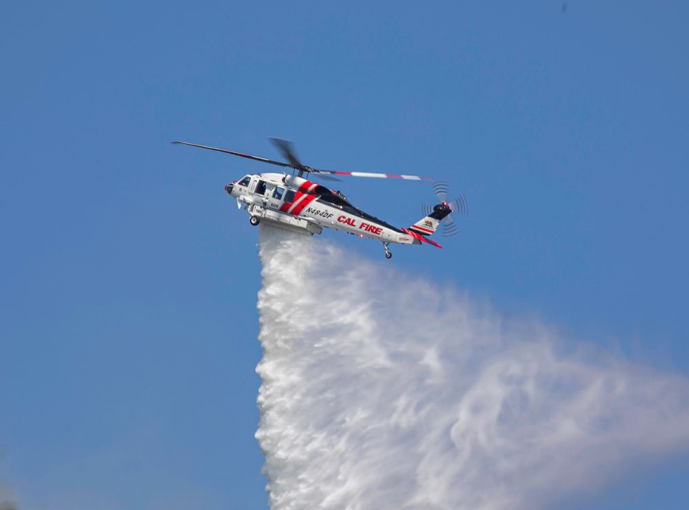 A CAL FIRE helicopter drops water 