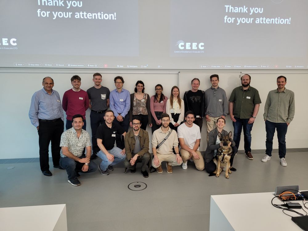 Group photo of CEEC project members at the all-hands meeting hosted at HLRS in Stuttgart. Around 20 people are standing and kneeling in two rows in front of a projection screen that reads “Thank you for your attention!” The group includes researchers and engineers from the consortium, with one person holding their guide dog in the front row.