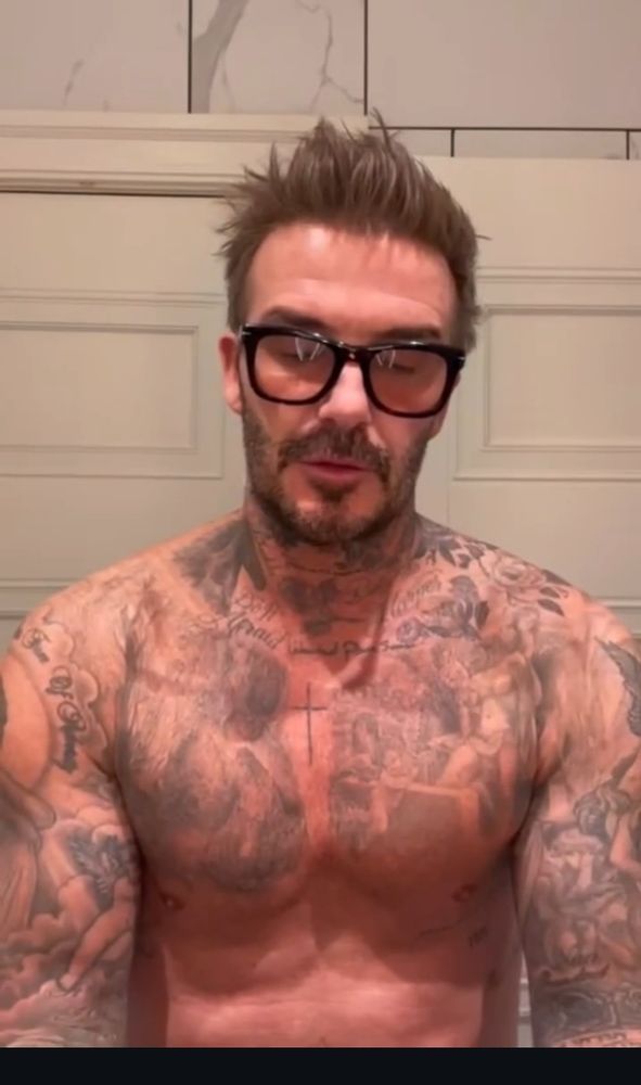 print de video do Instagram. david beckham de frente, sem camisa, usando oculos de armação grande e preta. cabelo penteado pra cima e todo tatudado