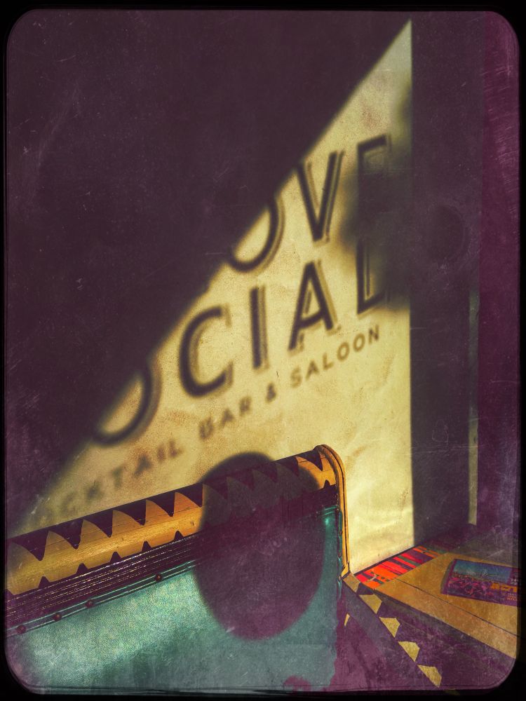 Reflection of door sign at Alcove Social in Alpine, TX