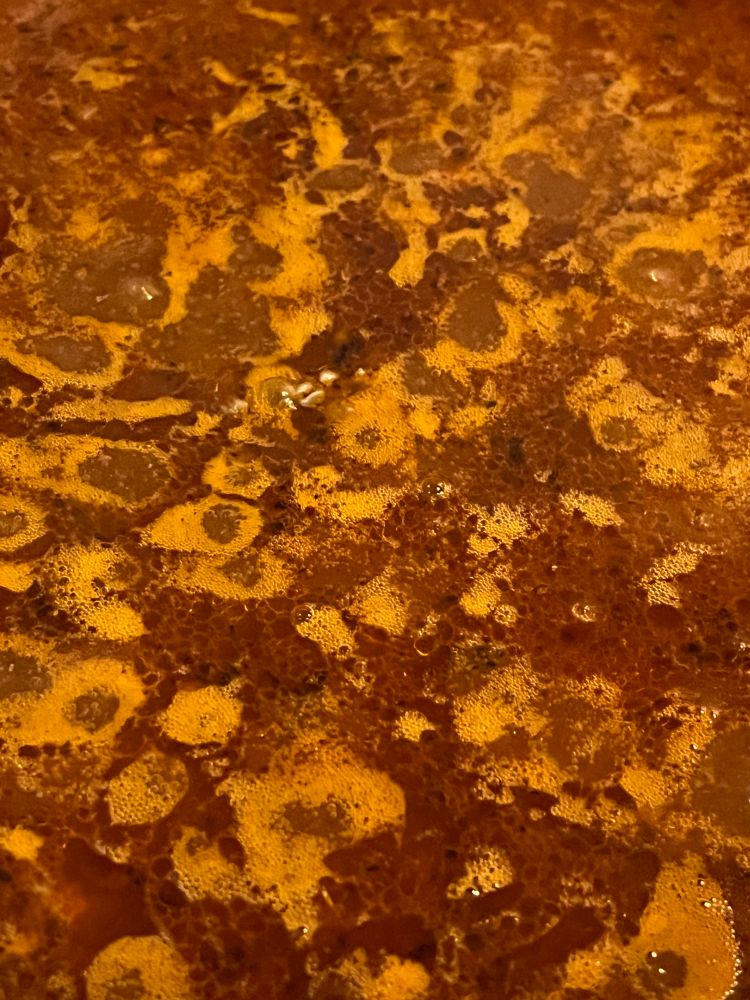 The surface of taco meat just beginning to simmer. It is mostly a dark red liquid with little bits of meat barely visible. We’ll be back to check on it after this bong hit