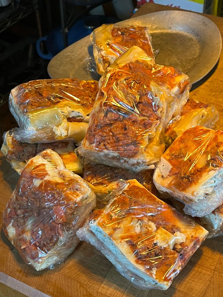 Single portions of lasagna individually wrapped on a wooden butcher’s block 