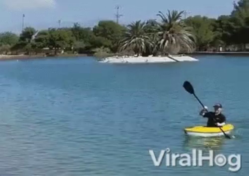 a man is paddling a yellow kayak in a lake with a small island in the background ..