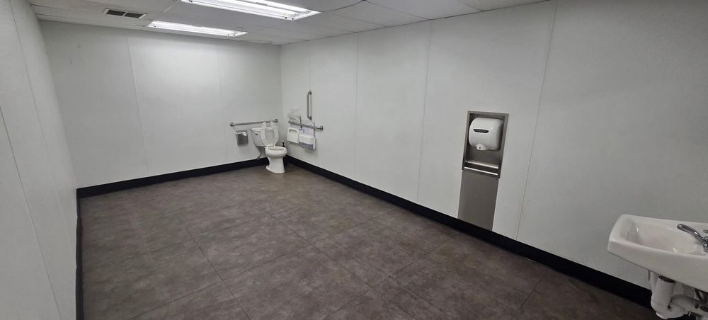 A bathroom but the room is very long with a toilet at one end, sink at the other. Tower dryer in the middle on the wall.