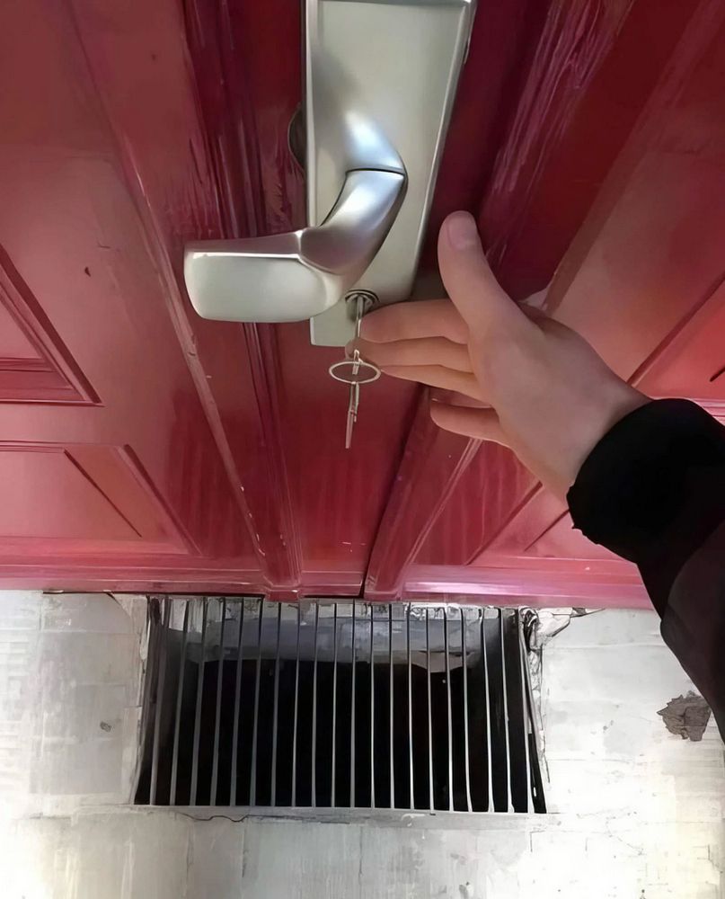 Someone putting in or taking out a key in a door outside a building with a grate right below so that is a key fall it would go straight through into the void.