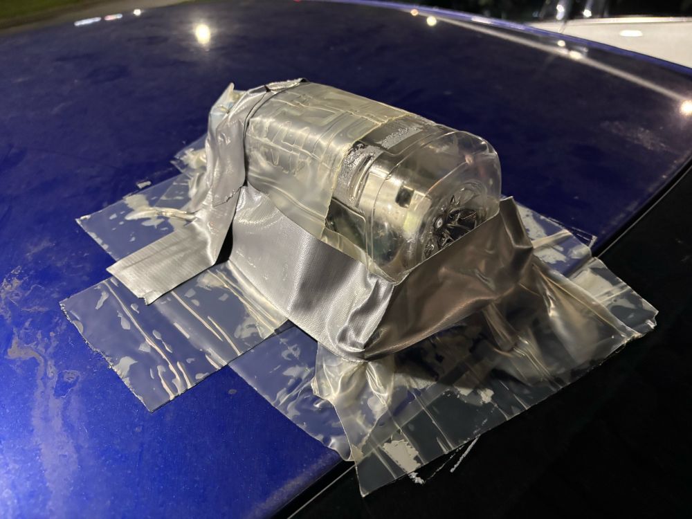 Gatorade bottle duct taped over a car antenna on a blue car.