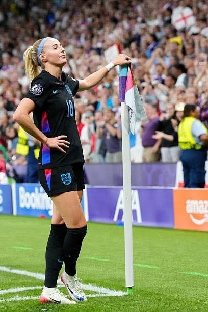 Chloe Kelly proudly posing by the corner flag having scored a goal