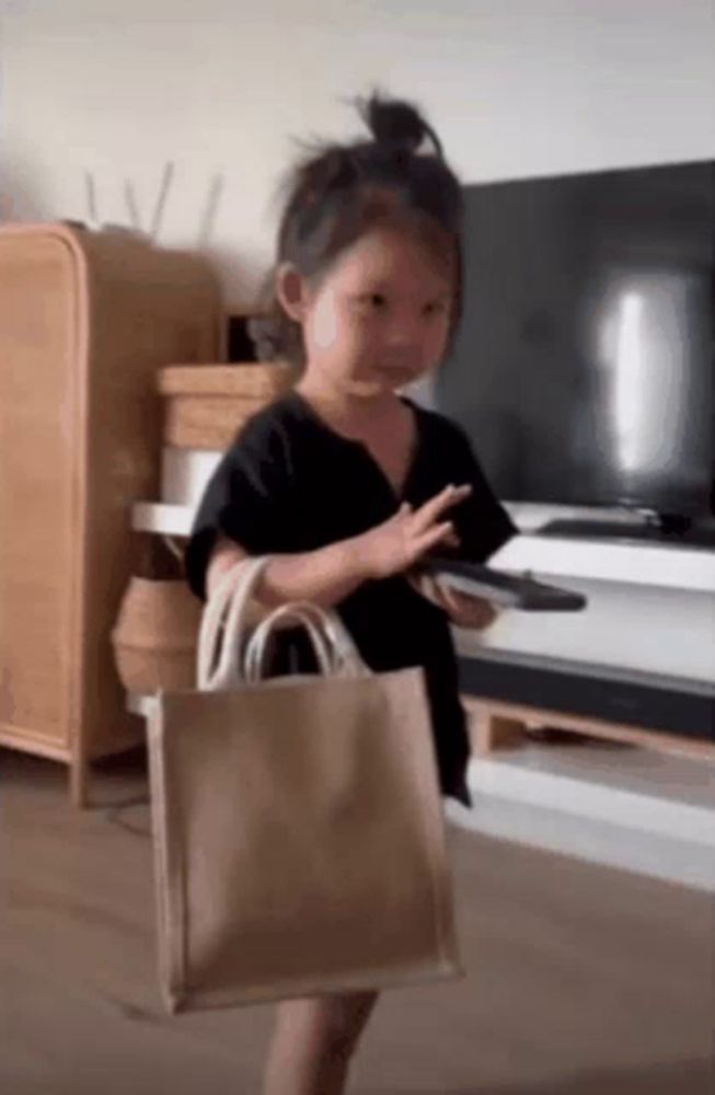 a little girl is holding a remote control and a bag in her hand .