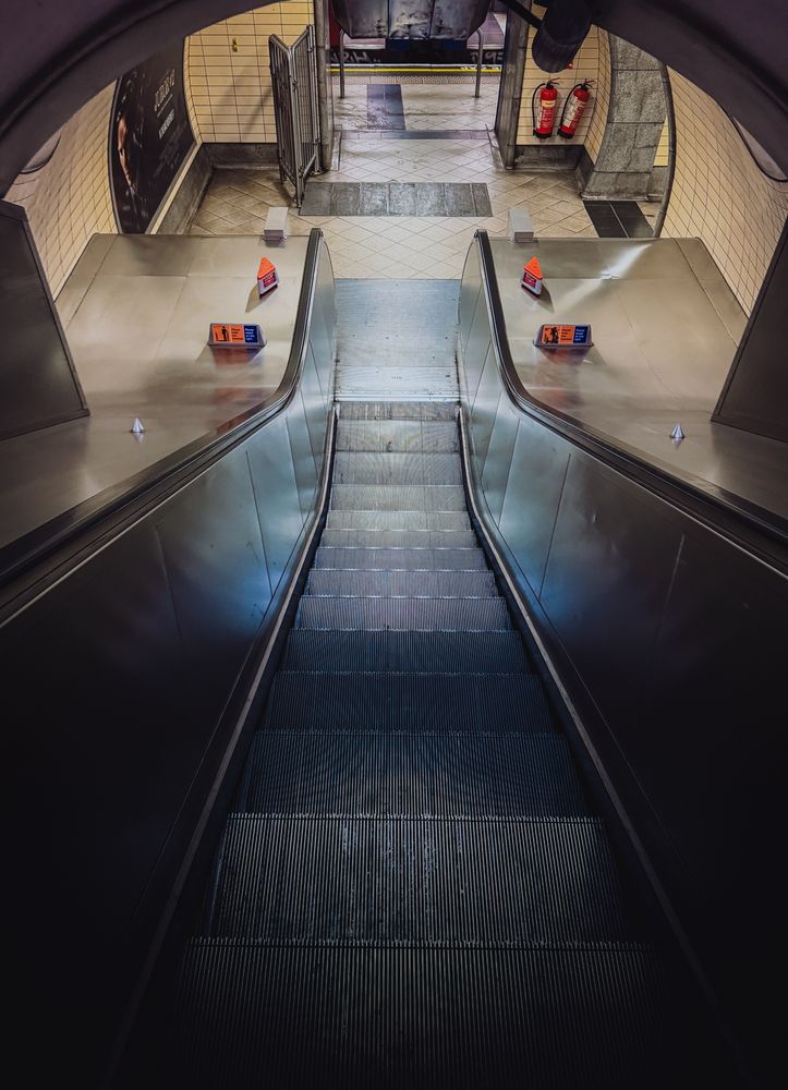 A dark escalator descends toward a tube platform